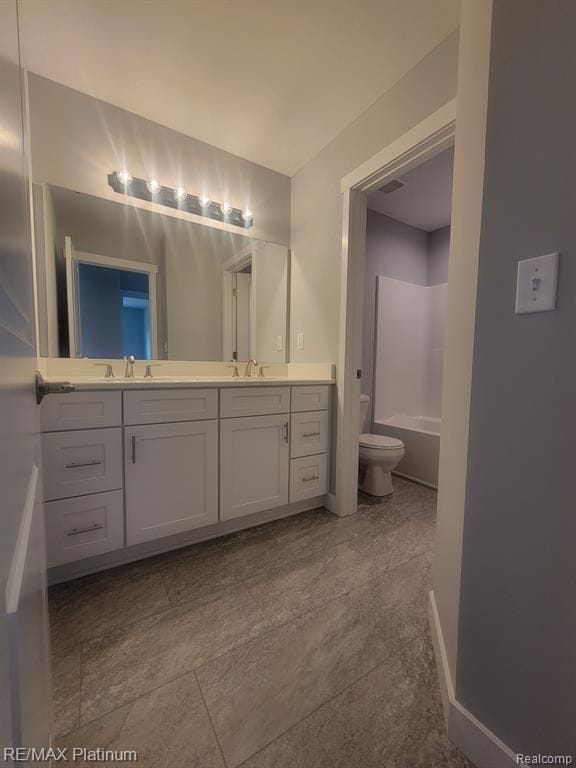 bathroom featuring baseboards, a sink, toilet, and double vanity