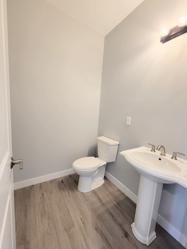 bathroom featuring a sink, wood finished floors, toilet, and baseboards