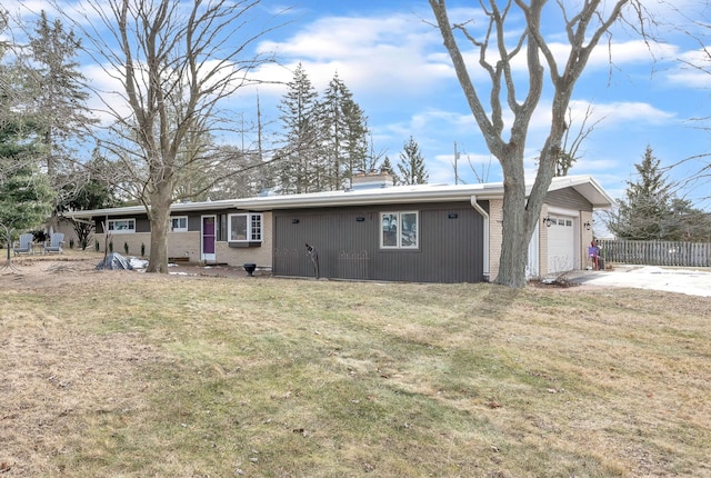 rear view of property featuring a garage, brick siding, and a lawn