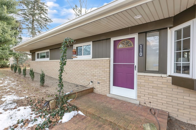 snow covered property entrance with brick siding