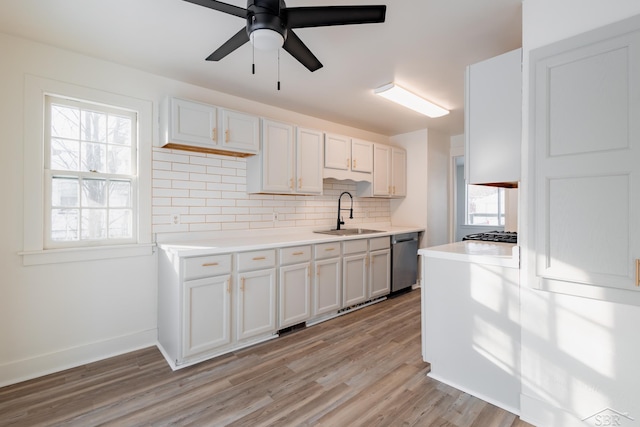 kitchen with dishwasher, light countertops, a sink, and white cabinetry