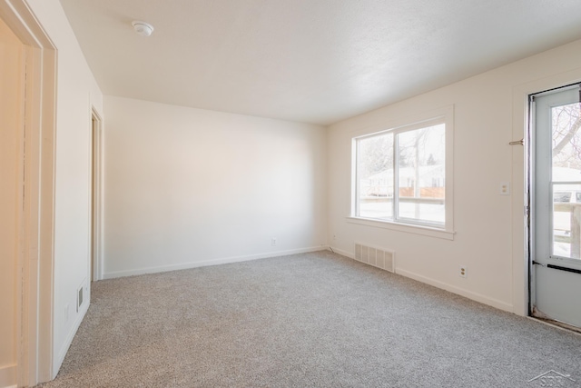 spare room featuring light carpet, baseboards, and visible vents