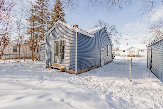 snow covered rear of property with a chimney