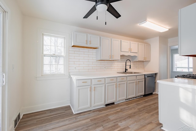 kitchen featuring light countertops, visible vents, white cabinetry, a sink, and dishwasher