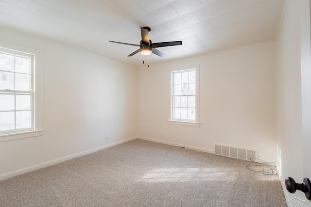 carpeted spare room featuring ceiling fan, ornamental molding, visible vents, and baseboards