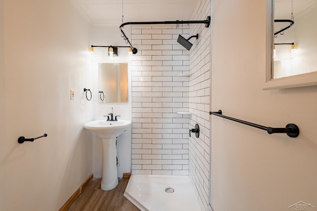 full bath with a stall shower, crown molding, a sink, and wood finished floors