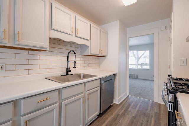 kitchen with tasteful backsplash, stainless steel appliances, light countertops, white cabinetry, and a sink