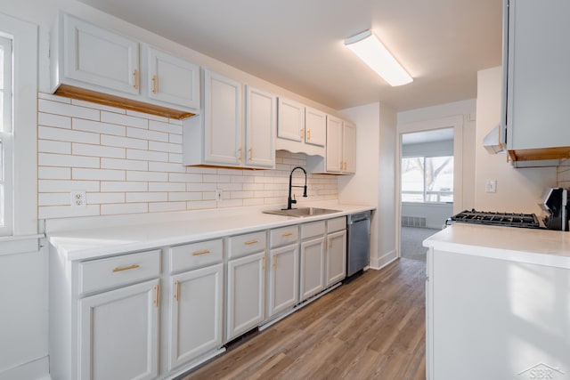 kitchen with stove, a sink, white cabinets, light countertops, and stainless steel dishwasher