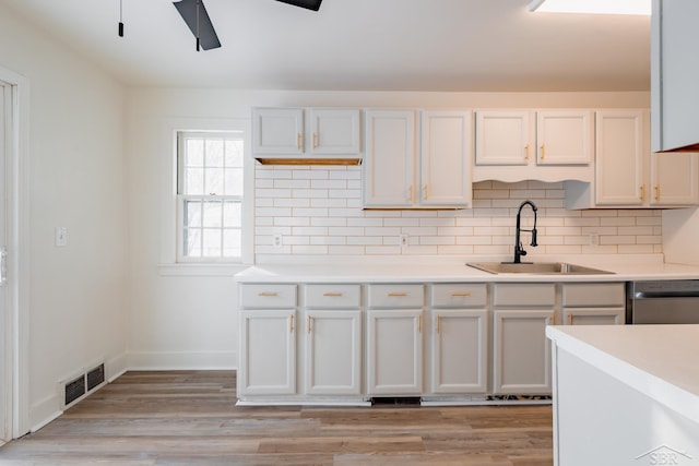 kitchen featuring light countertops, a sink, visible vents, and white cabinets