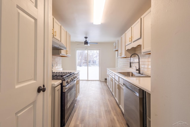 kitchen featuring decorative backsplash, stainless steel appliances, light countertops, under cabinet range hood, and a sink