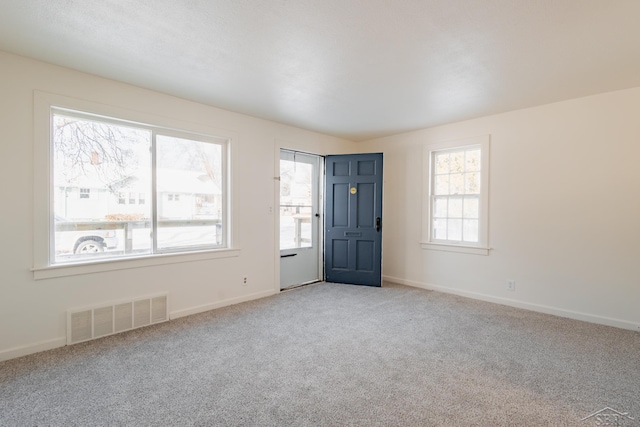 foyer entrance with carpet floors, baseboards, and visible vents