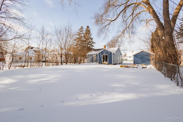 yard covered in snow with fence and an outbuilding