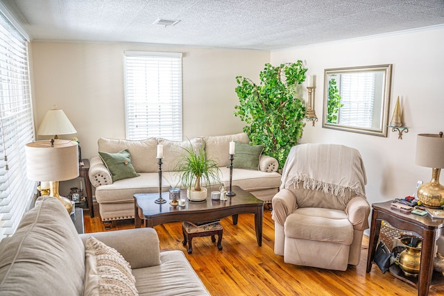 living area with a textured ceiling, visible vents, and wood finished floors