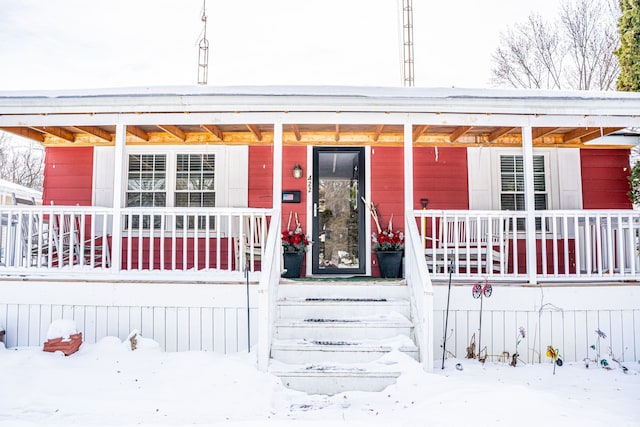 snow covered property entrance with a porch