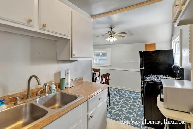 kitchen with ceiling fan, white cabinets, a sink, and light countertops