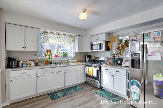 kitchen featuring stainless steel appliances, white cabinets, and light wood finished floors