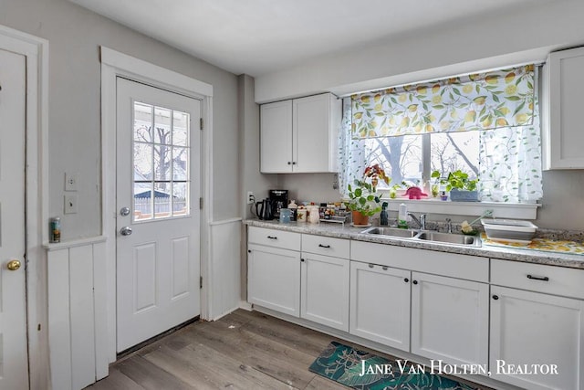 kitchen with light countertops, white cabinetry, a sink, and light wood-style flooring