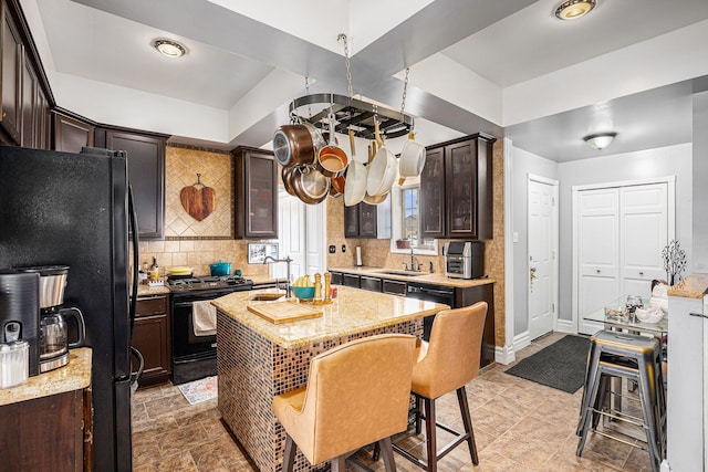 kitchen featuring a sink, a kitchen island, dark brown cabinets, black appliances, and tasteful backsplash