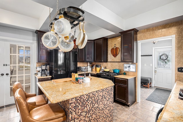 3342 Oak Grove Rd, Howell, MI 48855 - kitchen featuring dark brown cabinetry, a kitchen island with sink, a breakfast bar area, tasteful backsplash, and black appliances