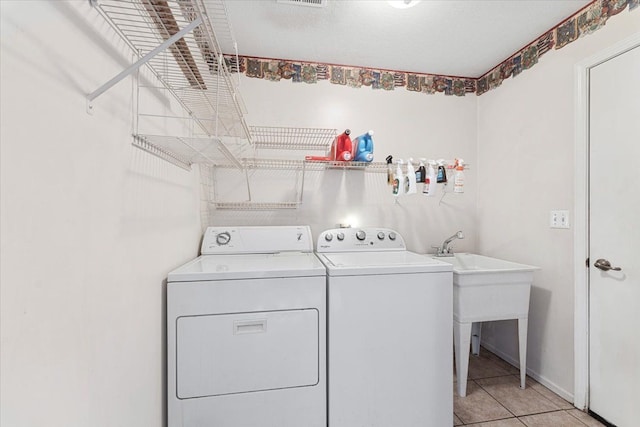 washroom featuring laundry area, visible vents, washing machine and clothes dryer, and light tile patterned floors