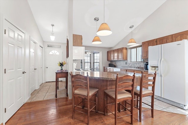 kitchen with light wood-style floors, lofted ceiling, white appliances, and brown cabinets