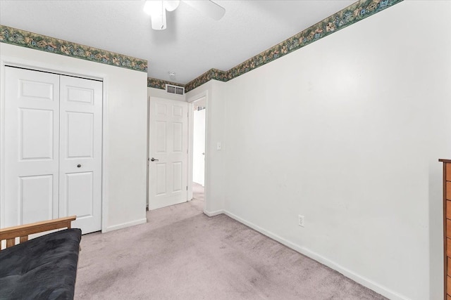 unfurnished bedroom featuring light carpet, baseboards, visible vents, ceiling fan, and a closet