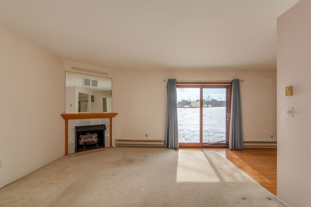 unfurnished living room featuring carpet, visible vents, a tiled fireplace, and baseboard heating