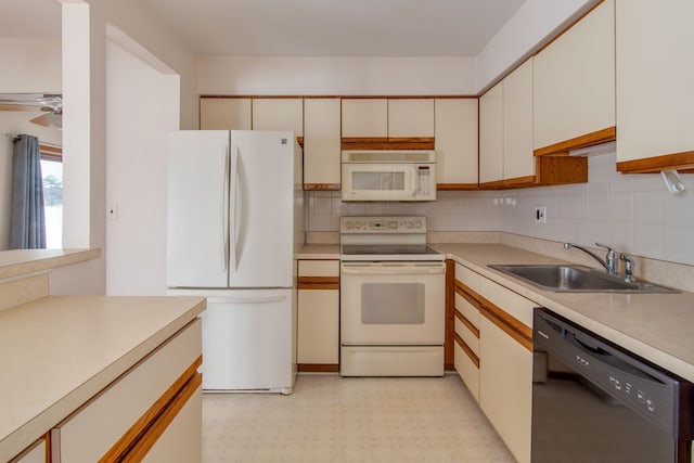 kitchen with light countertops, white appliances, light floors, and a sink