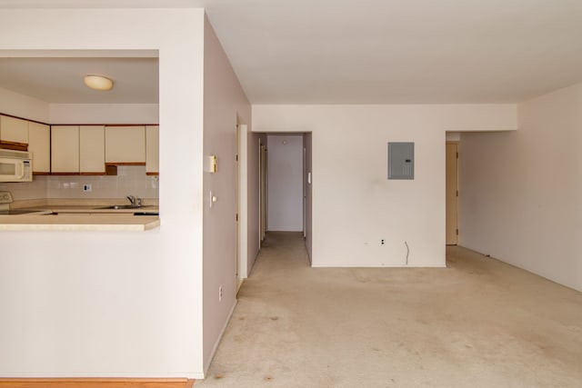 kitchen featuring white microwave, range with electric cooktop, light countertops, backsplash, and electric panel