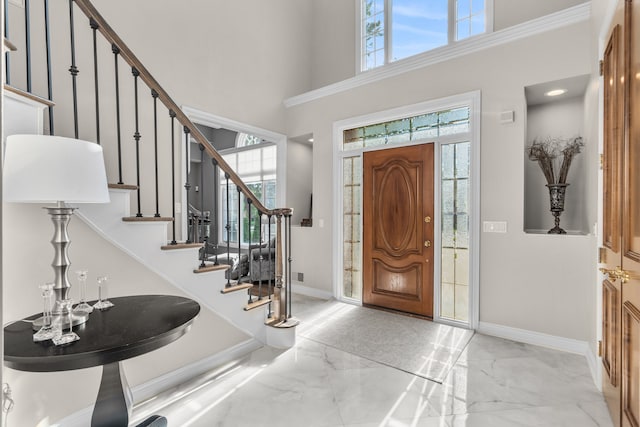 foyer with a towering ceiling, marble finish floor, stairs, and baseboards