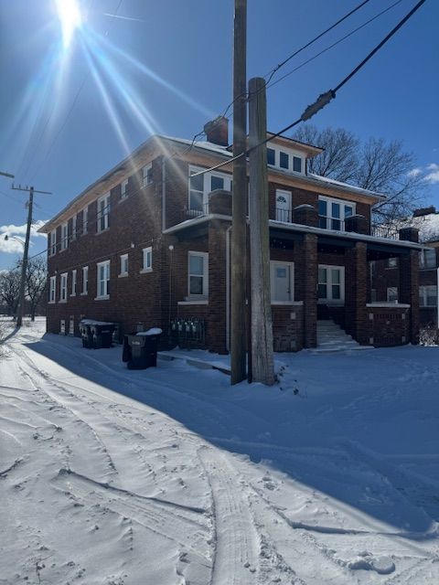 snow covered house featuring brick siding