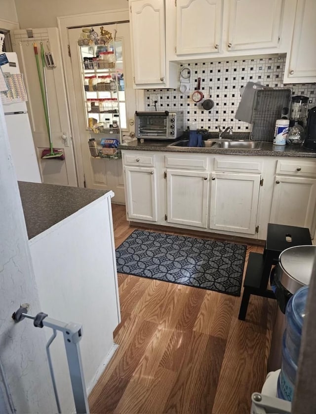 kitchen featuring dark countertops, white cabinets, and a sink