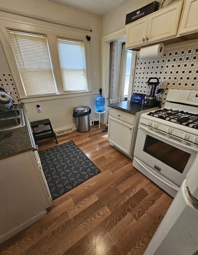 kitchen featuring dark countertops, a sink, visible vents, and white range with gas stovetop