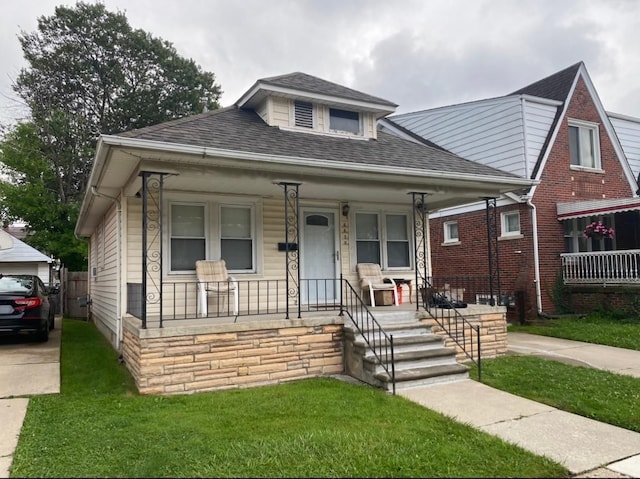 bungalow-style house with a porch, a front lawn, and a shingled roof