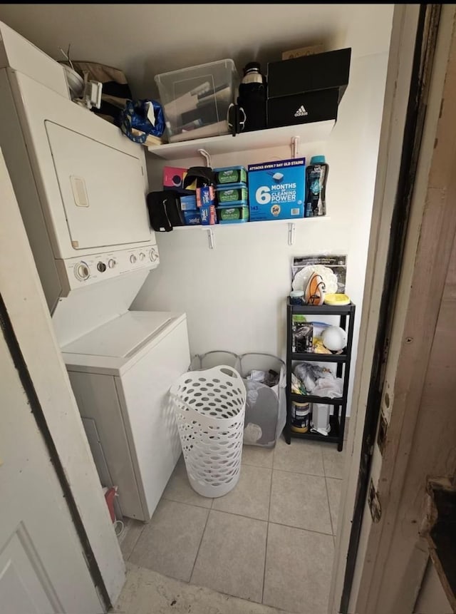 laundry room with laundry area, light tile patterned flooring, and stacked washer / drying machine