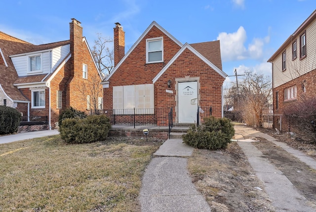 view of front of property featuring a front yard, brick siding, and roof with shingles