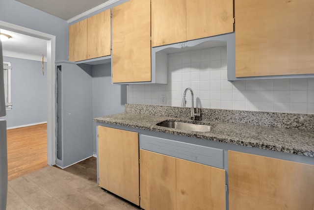 kitchen featuring baseboards, a sink, light stone countertops, light wood-type flooring, and backsplash