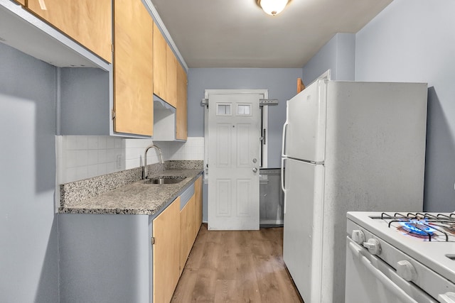 kitchen featuring light stone counters, white range with gas stovetop, a sink, decorative backsplash, and light wood finished floors