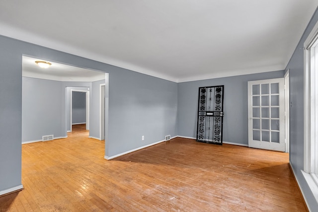 unfurnished room with visible vents, baseboards, and hardwood / wood-style flooring