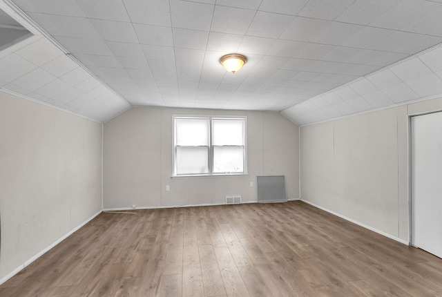 additional living space with lofted ceiling, visible vents, and wood finished floors