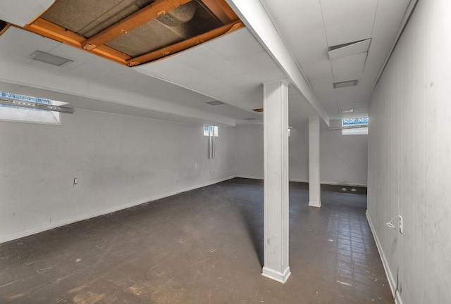 basement featuring visible vents, baseboards, and a drop ceiling