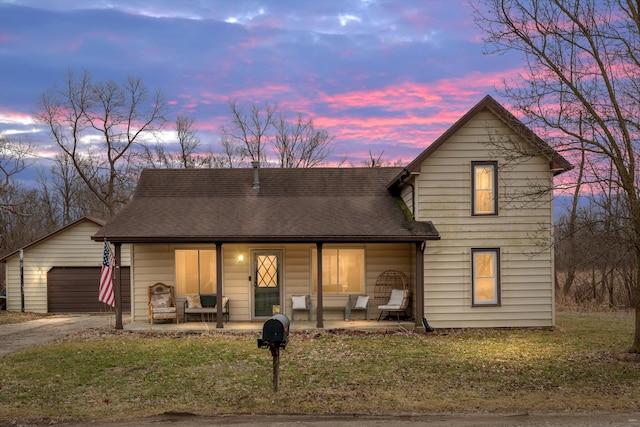 traditional home with a garage, a shingled roof, a lawn, and a porch