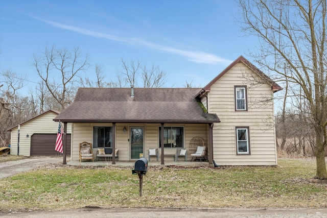 traditional-style home with an outdoor structure, a front yard, a porch, and roof with shingles