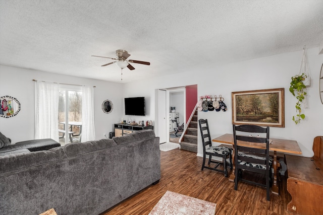 living room with stairs, dark wood-type flooring, a textured ceiling, and a ceiling fan