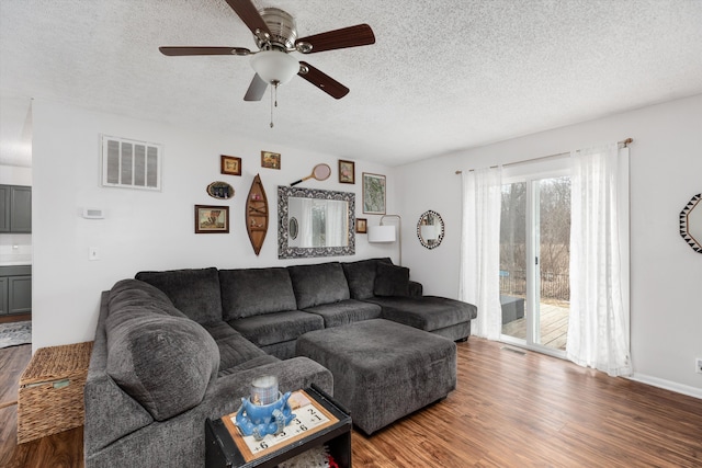 living area featuring a textured ceiling, visible vents, and wood finished floors