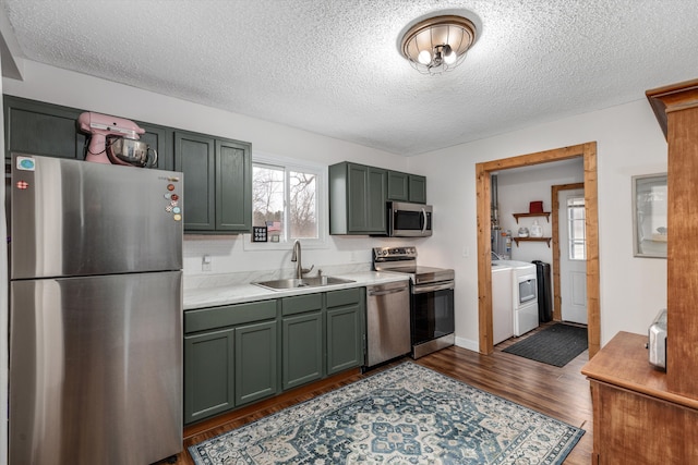 kitchen featuring stainless steel appliances, light countertops, dark wood-type flooring, a sink, and green cabinetry