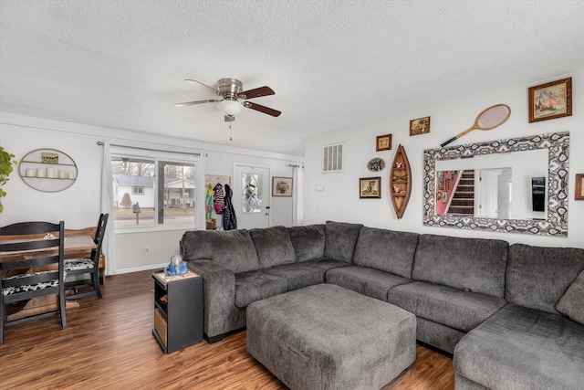 living room featuring baseboards, visible vents, ceiling fan, wood finished floors, and a textured ceiling