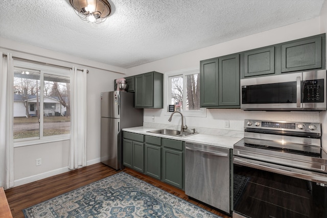 kitchen with stainless steel appliances, dark wood-type flooring, a sink, baseboards, and light countertops