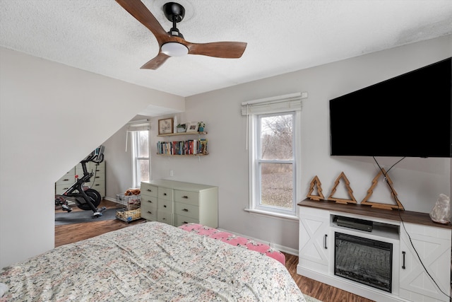 bedroom with baseboards, a textured ceiling, a ceiling fan, and wood finished floors