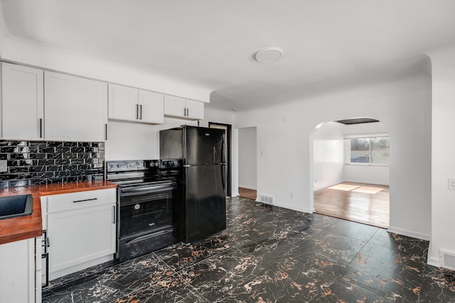 kitchen featuring arched walkways, white cabinets, wooden counters, black appliances, and tasteful backsplash